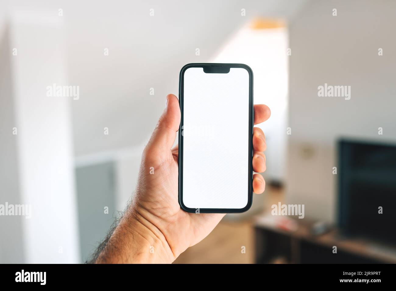 Smartphone-Mockup, Internet der Dinge und Smart-Home-Konzept, Mann mit Mobiltelefon. Nahaufnahme der Handhaltevorrichtung mit leerem Bildschirm im Home Interi Stockfoto