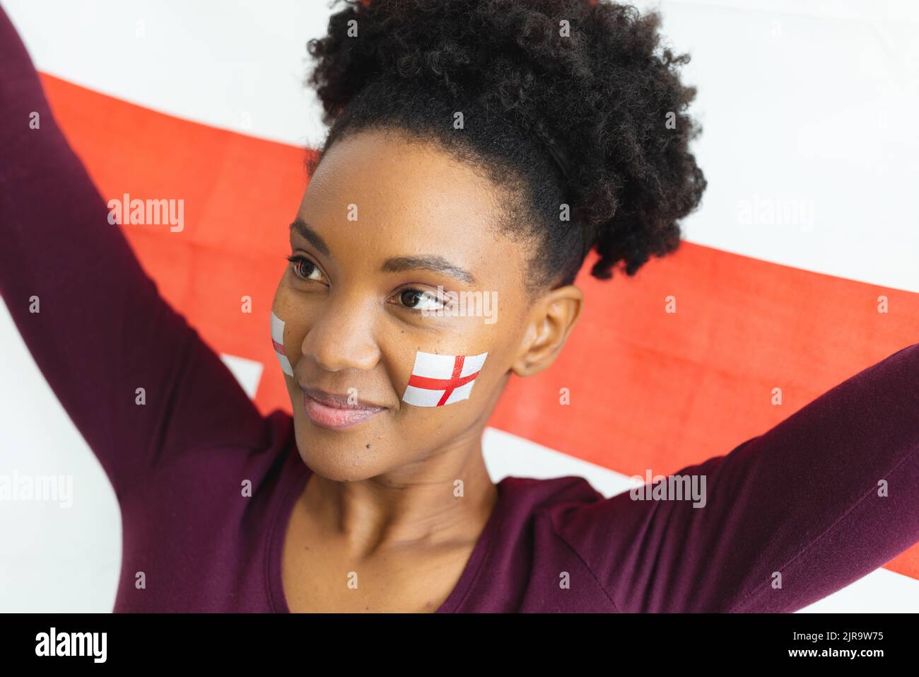 Bild einer glücklichen afroamerikanischen Frau mit Flaggen englands auf dem Gesicht über der Flagge englands Stockfoto