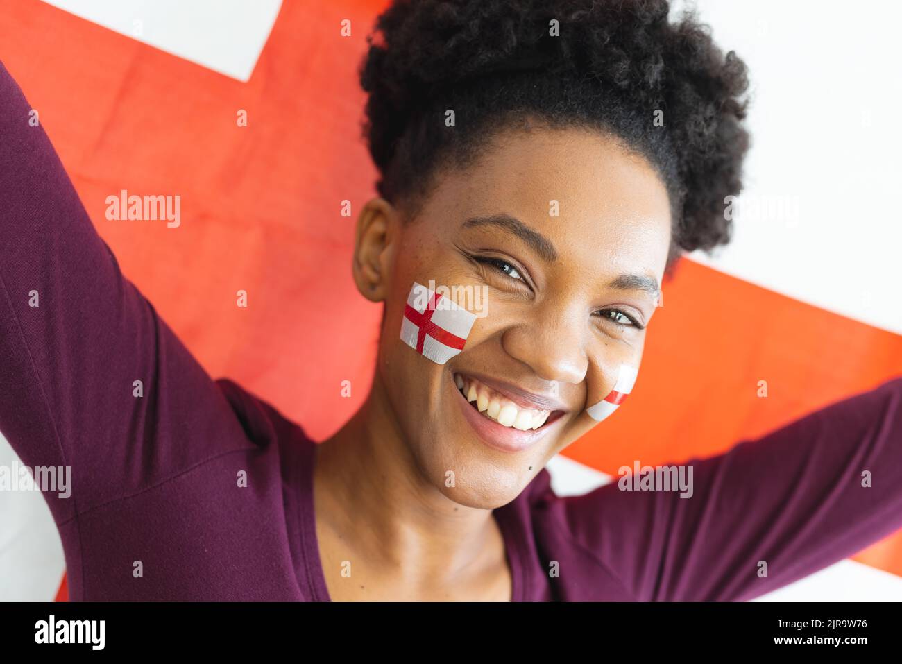 Bild einer glücklichen afroamerikanischen Frau mit Flaggen englands auf dem Gesicht über der Flagge englands Stockfoto