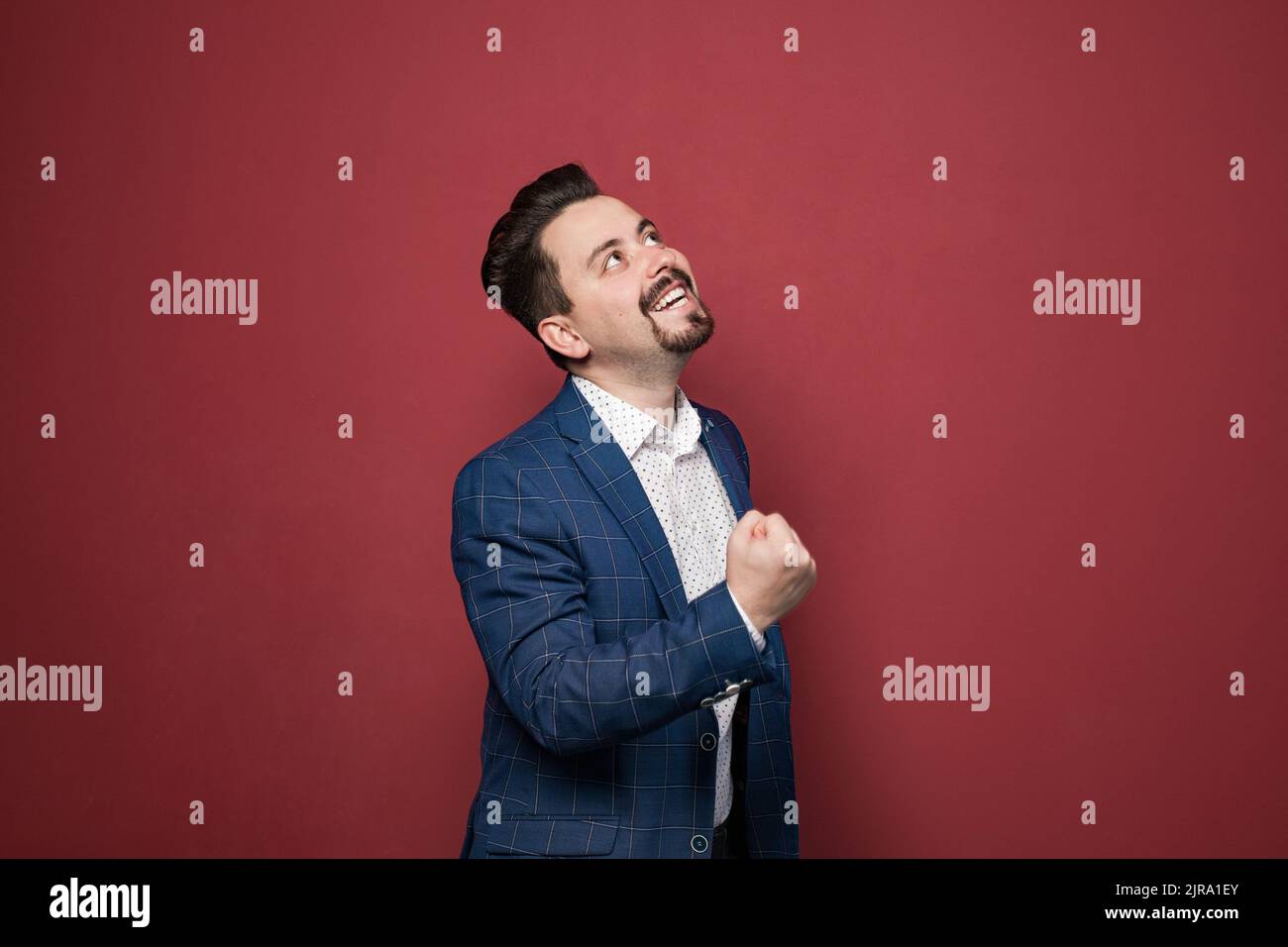 Porträt eines verspielten bärtigen Geschäftsmannes, der Spaß hat und aufschaut. Männer tragen Anzug im offiziellen Stil. Innenaufnahme im Studio Stockfoto