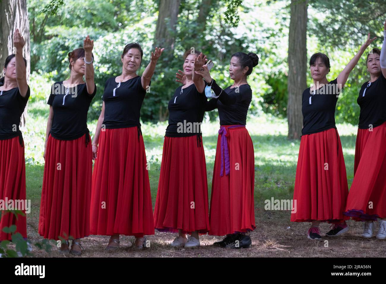 Chinesische amerikanische Tänzer im mittleren Alter Proben mit Hilfe ihres Lehrers in einem Park in Queens, New York City. Stockfoto