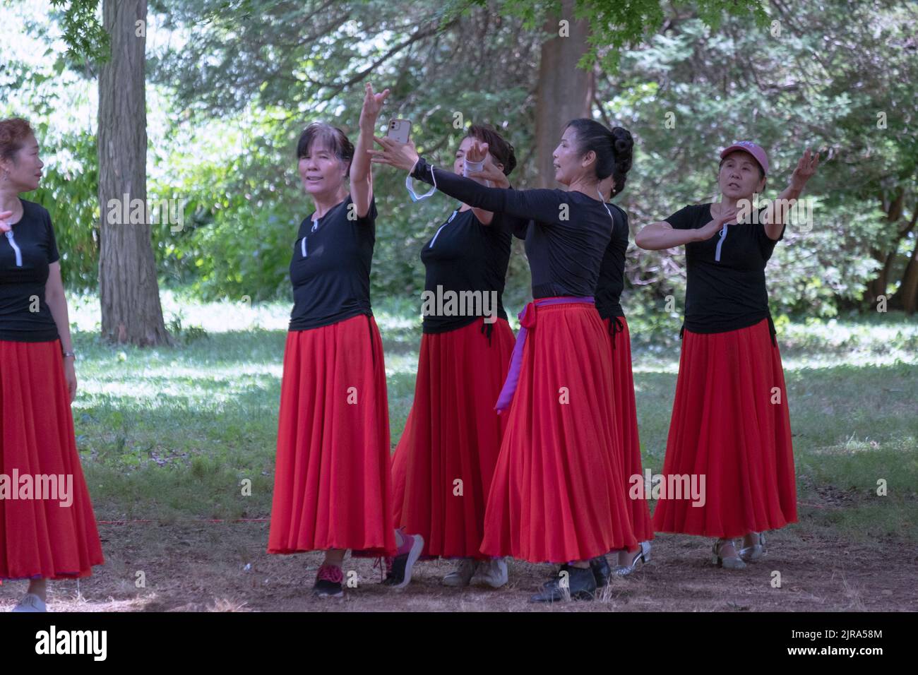 Chinesische amerikanische Tänzer im mittleren Alter Proben mit Hilfe ihres Lehrers in einem Park in Queens, New York City. Stockfoto