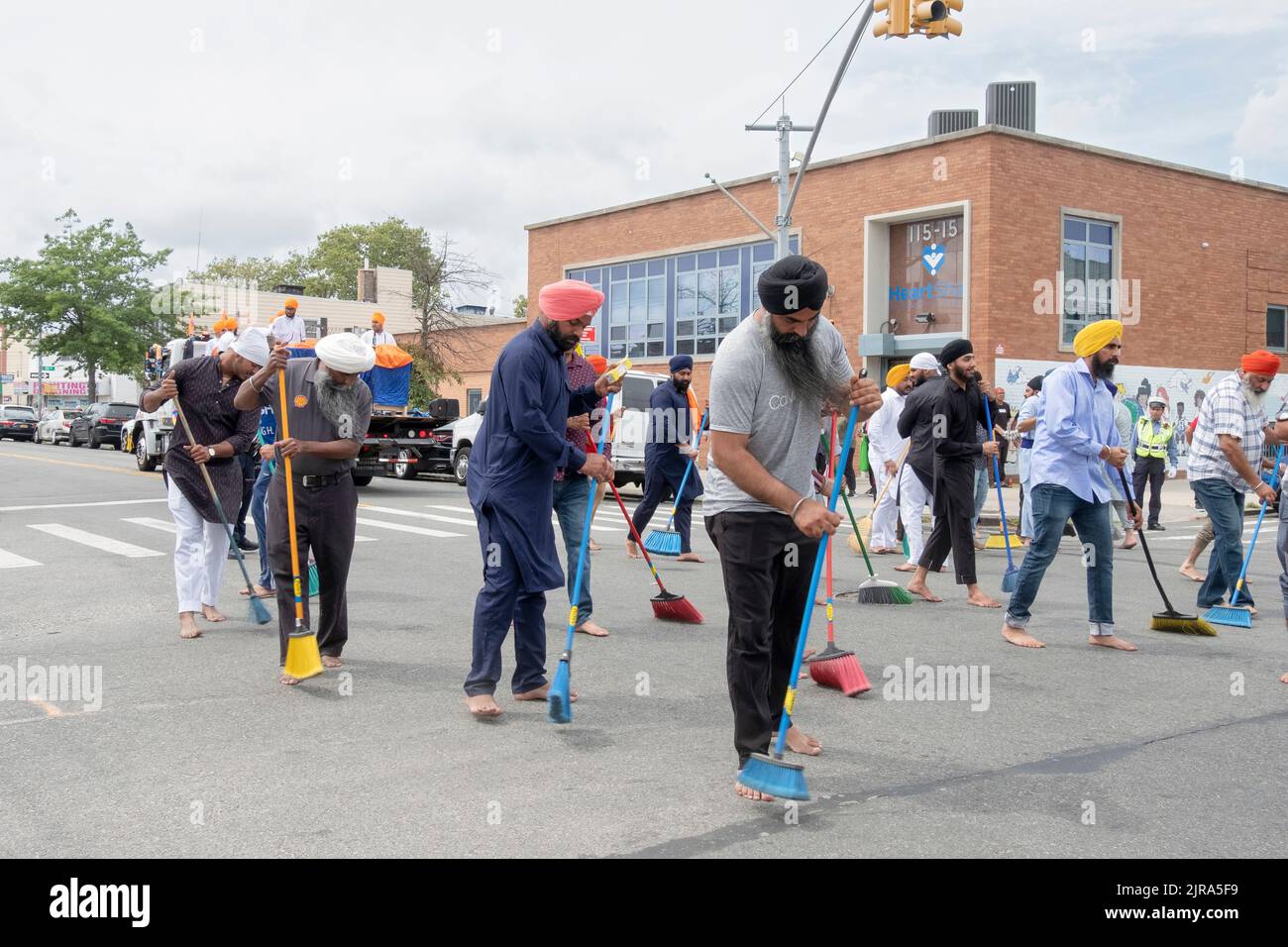 Fromme Sikh Männer und Frauen fegen die Liberty Avenue, wo ein Festwagen mit ihrem heiligen Buch Guru Granth Sahib vorbeifahren wird. Bei der Nagar Kirtan Parade. Stockfoto