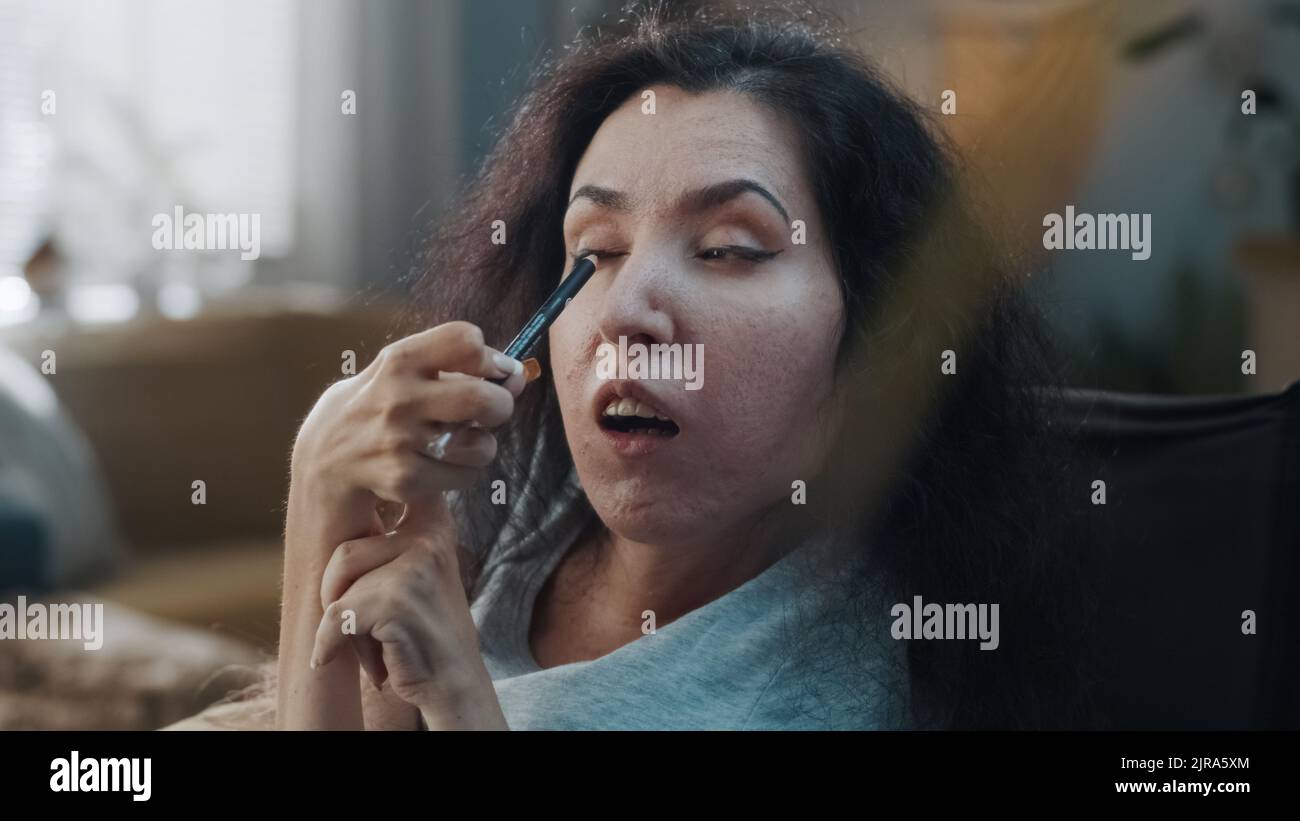 Schöne hübsche Frau mit einer Behinderung macht einen Abend Make-up mit Eyeliner in gemütlichen Hause am Tag Stockfoto