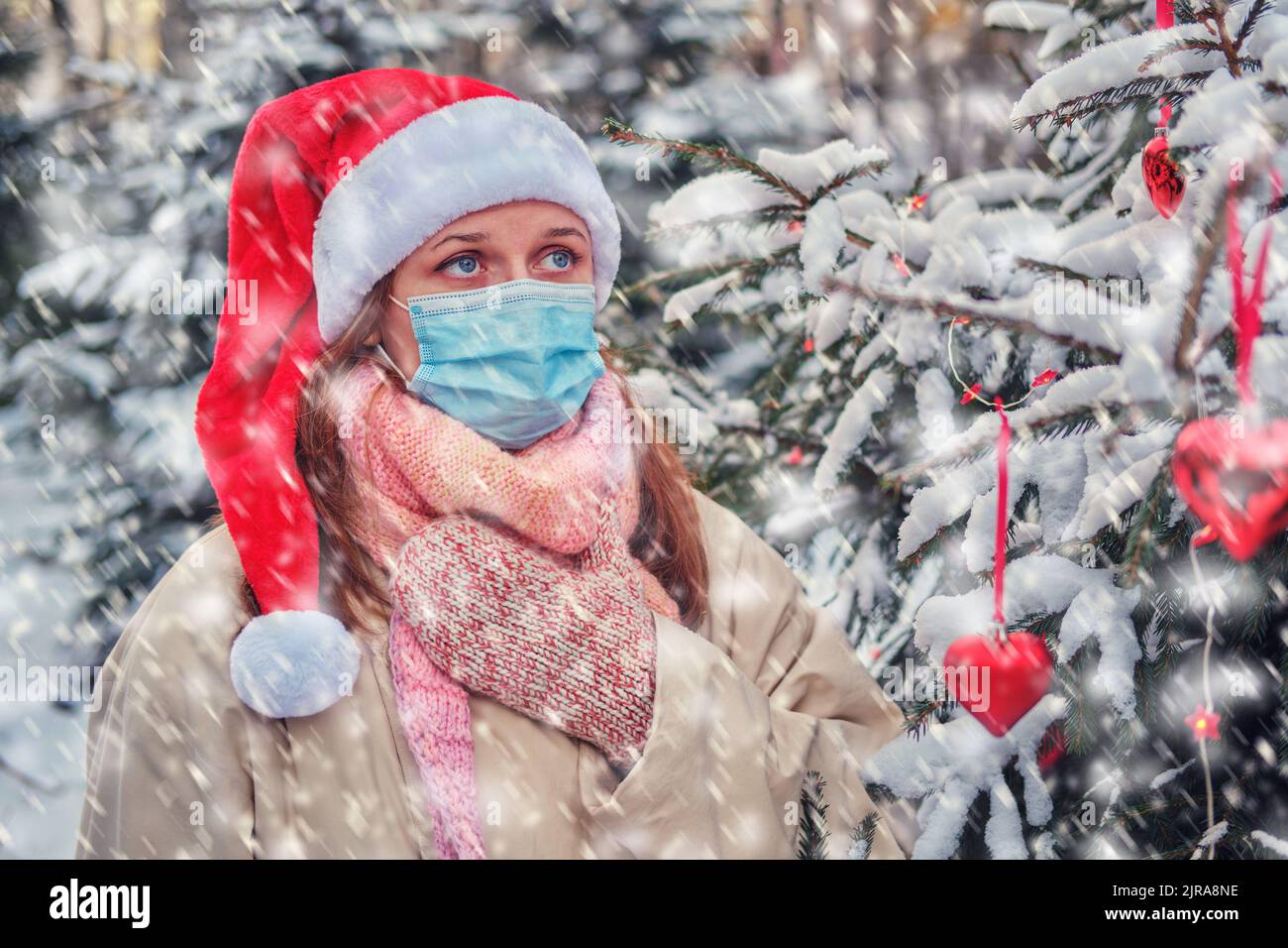 Eine Frau hustet und hält in der Winternatur am Silvesterabend Halsschmerzen an einem Weihnachtsbaum Stockfoto