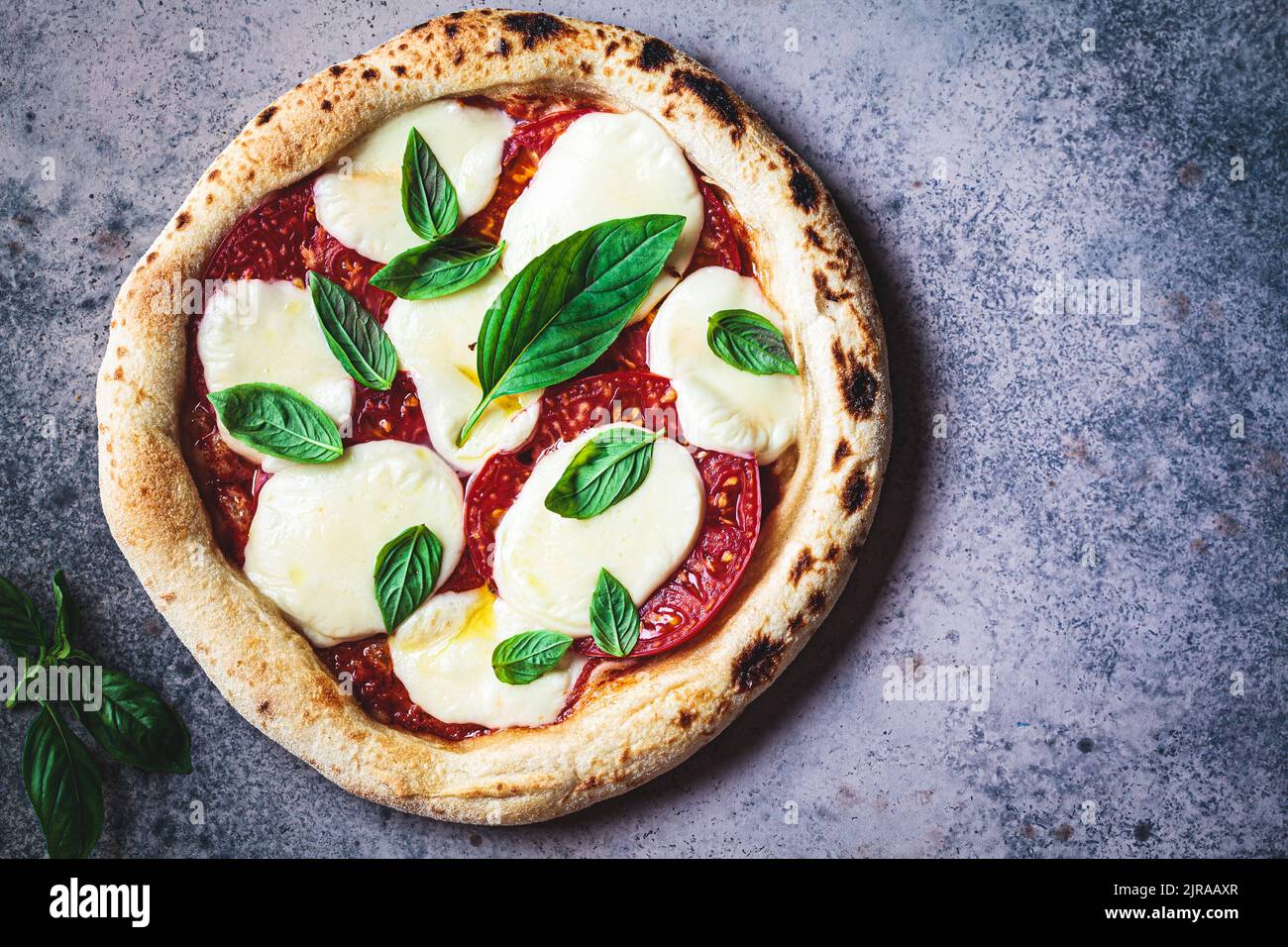 Klassische neopolitanische margherita Pizza mit Tomaten, Mozzarella und Basilikum auf dunklem Hintergrund, Draufsicht. Stockfoto