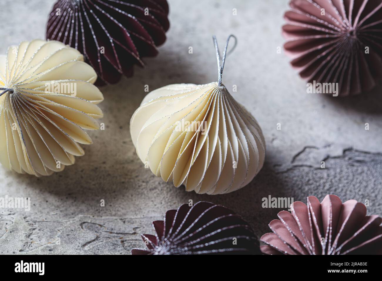 Papier handgemachte Weihnachtsbaumkugeln in verschiedenen Farben close-up auf grauem Hintergrund. Umweltfreundlich, keine Abfälle, Dekoration für den Urlaub. Stockfoto