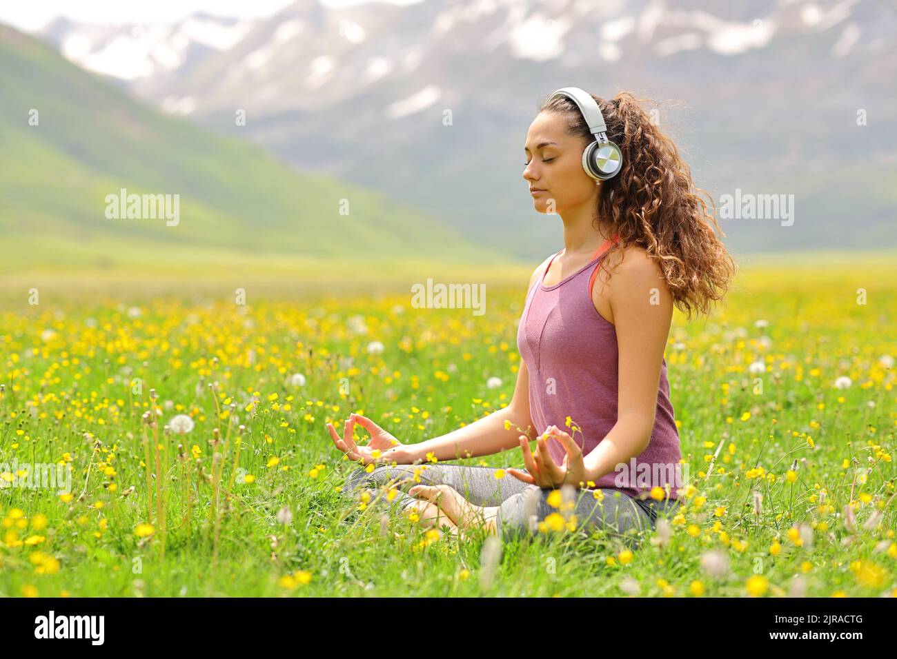 Yogi macht geführte Yogatutorial mit Kopfhörern im Berg Stockfoto