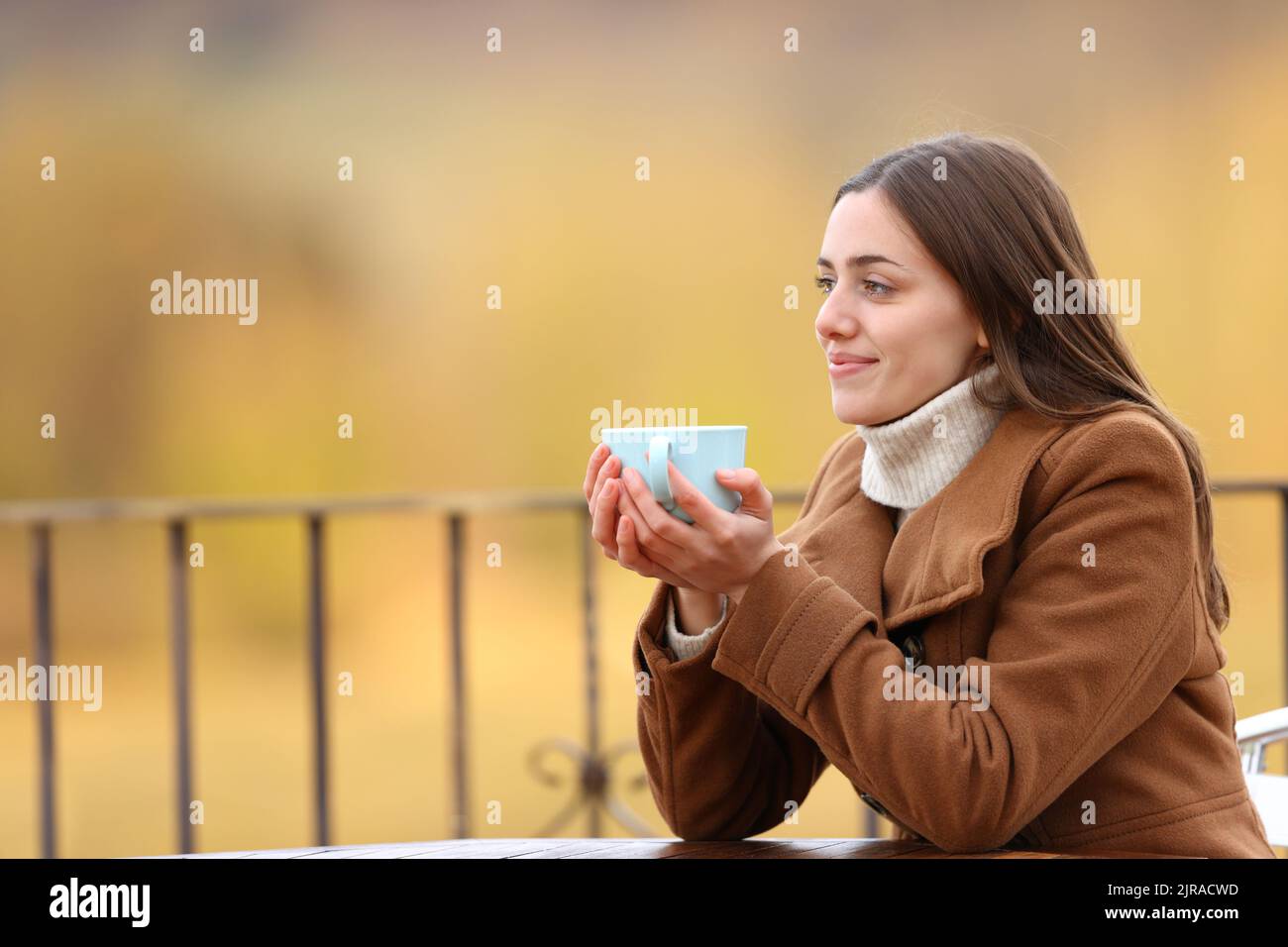 Frau, die sich im Winter ausruhte und Kaffee trank, blickte auf eine Terrasse Stockfoto