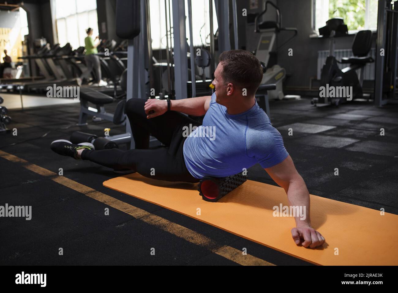 Männliche Bodybuilder Stretching im Fitnessstudio, mit Schaumstoffrolle Stockfoto
