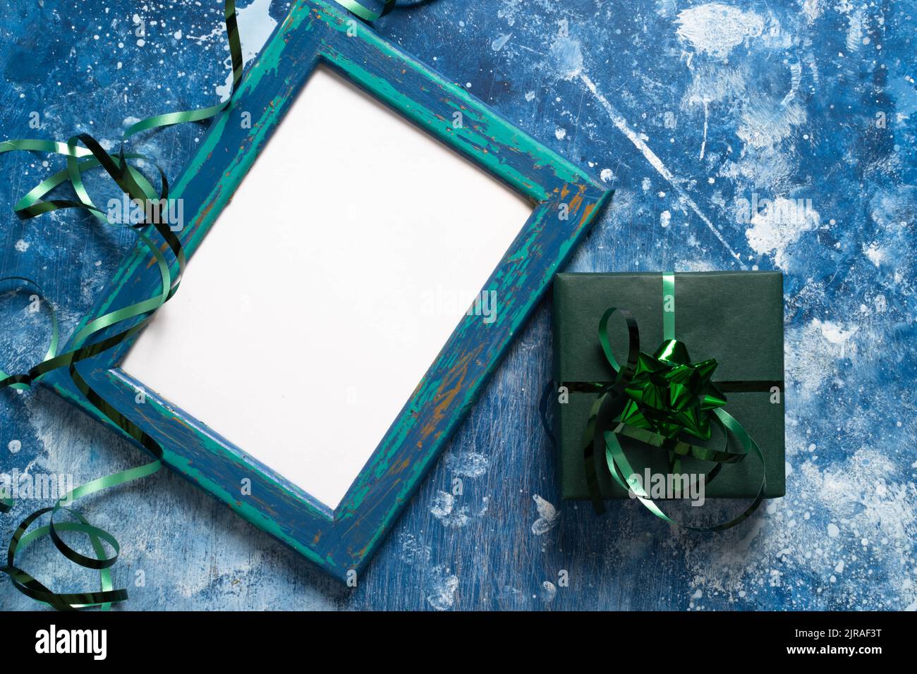 Festliche Feiertage Neujahr und Weihnachten grüne Geschenkbox auf blauem abstrakten Hintergrund. Konzept von Karneval, Geburtstag, Party. Kopieren Raum, Rahmen, guter Hintergrund für Ihr Design. Flach liegend. Draufsicht Stockfoto
