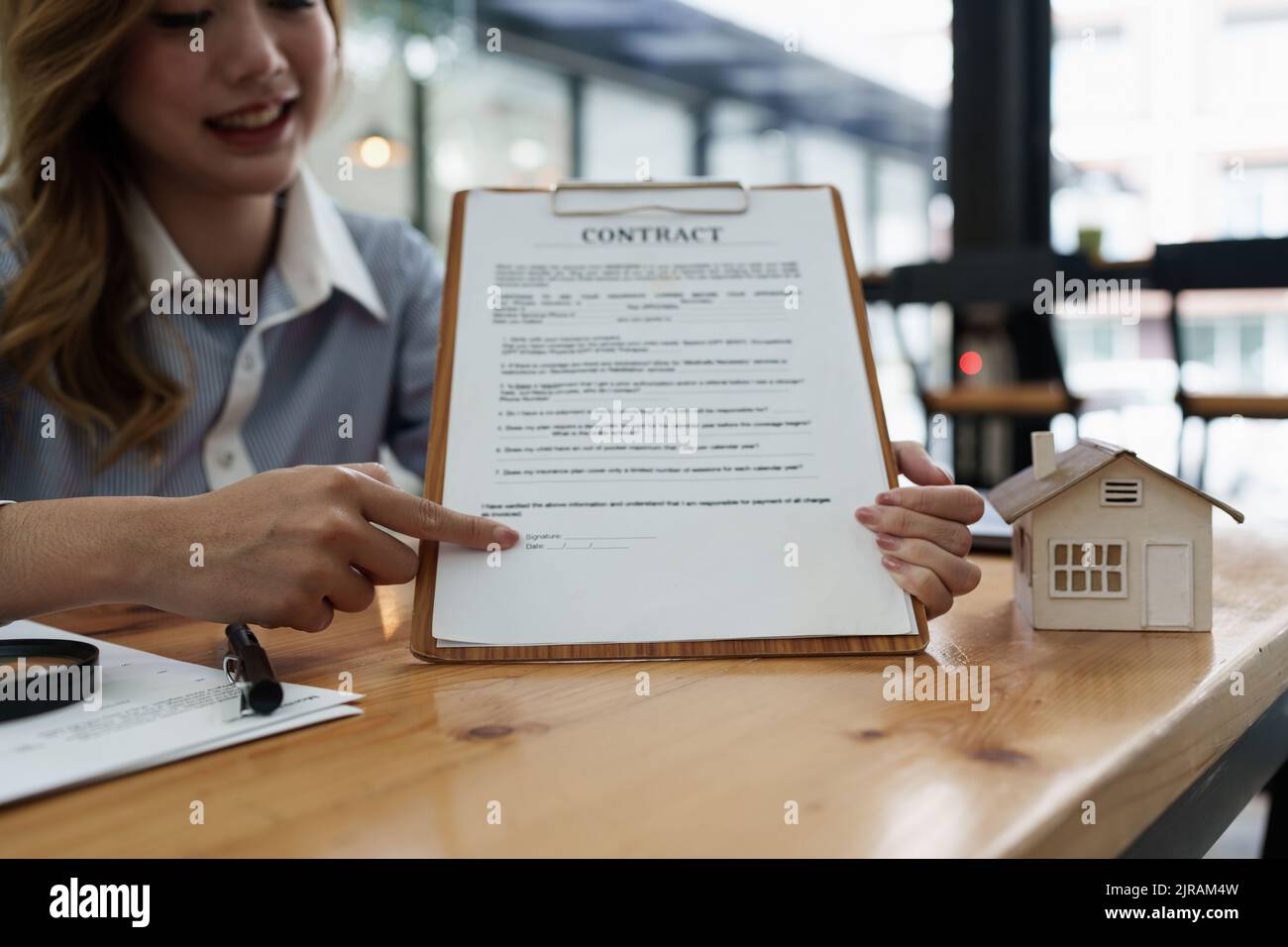 Geschäftsfrau oder Agent zeigt und unterzeichnet Vereinbarung für den Kauf von Haus. Konzept des Bankleiters Stockfoto