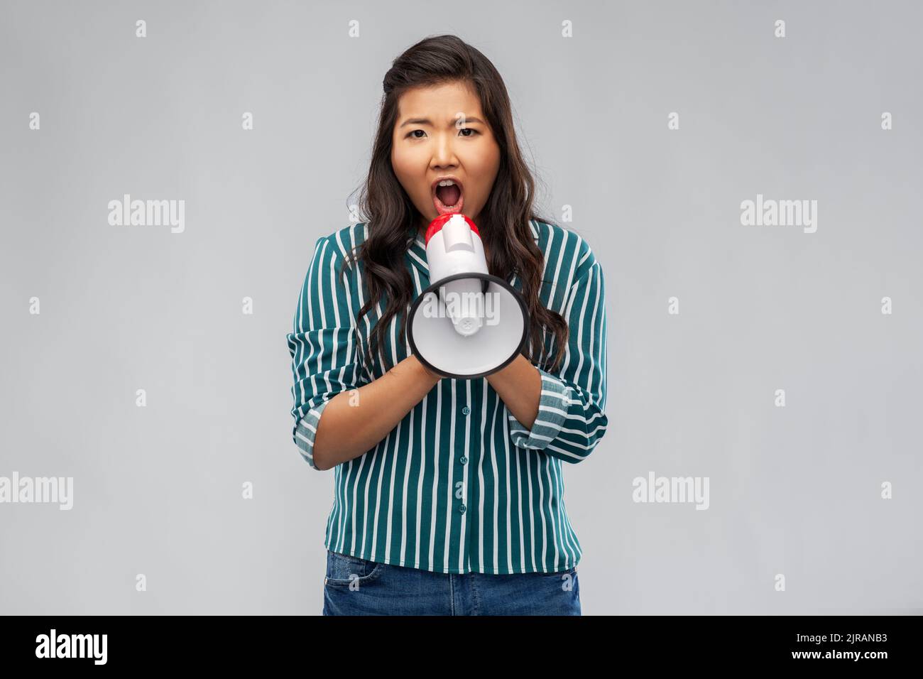 Wütende junge asiatische Frau, die mit Megaphon spricht Stockfoto
