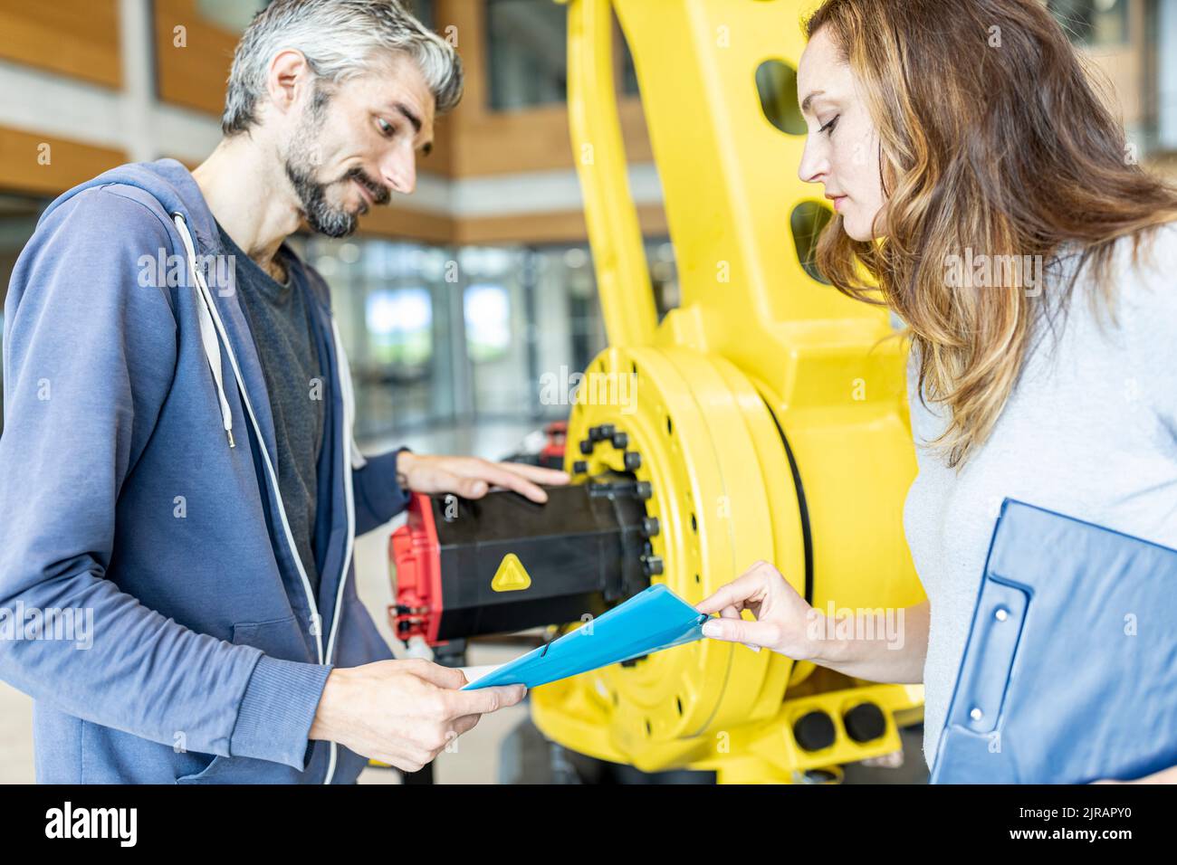 Techniker treffen sich vor einem Industrieroboter Stockfoto