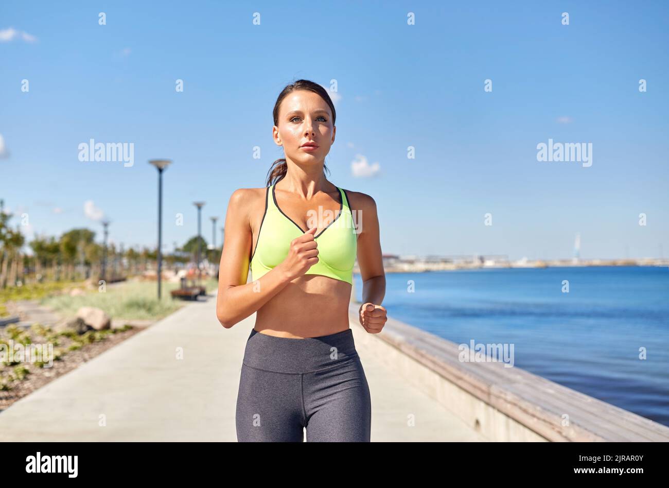 Junge Frau, die entlang der Seepromenade läuft Stockfoto