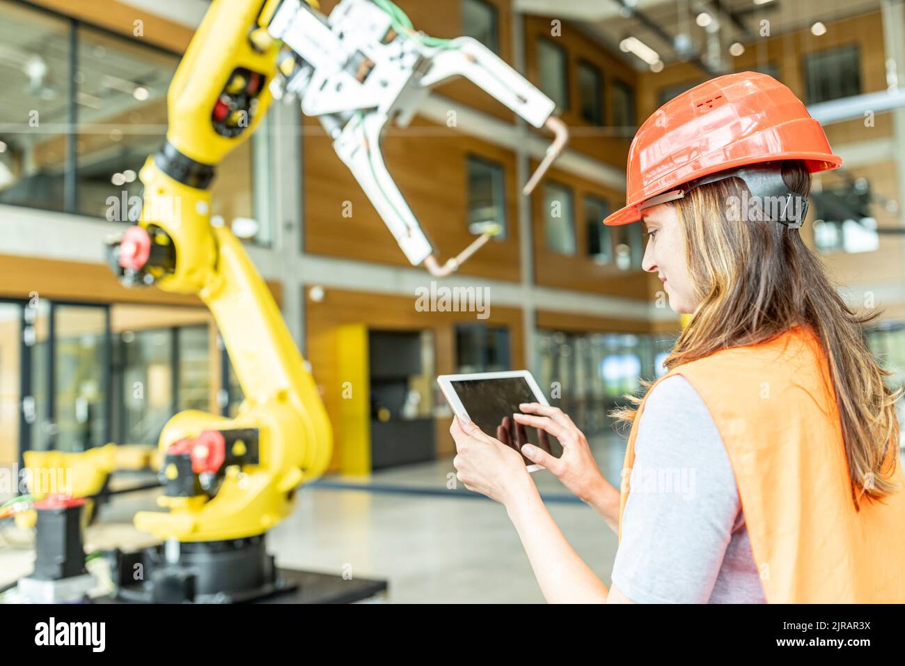 Facharbeiter, die Roboterarm mit digitalem Tablet steuern Stockfoto