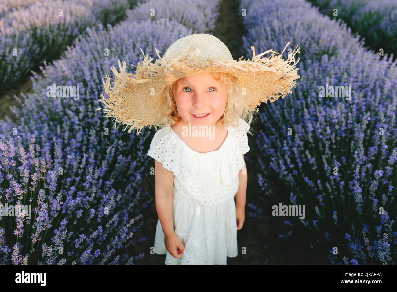 Lächelnd nettes Mädchen trägt Strohhut im Lavendelfeld stehen Stockfoto