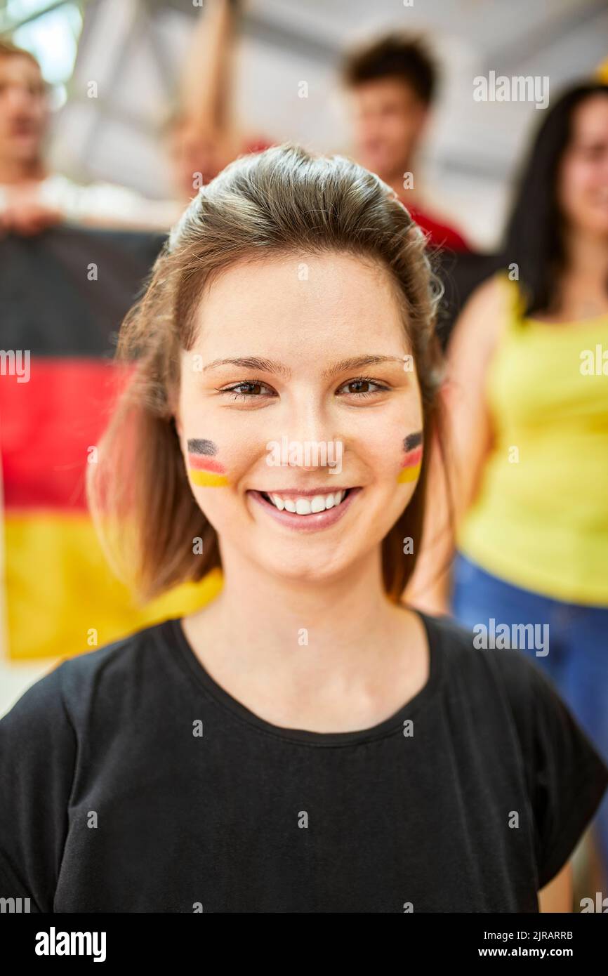 Lächelnde Frau mit der deutschen Flagge auf dem Gesicht bei einem Sportereignis im Stadion Stockfoto