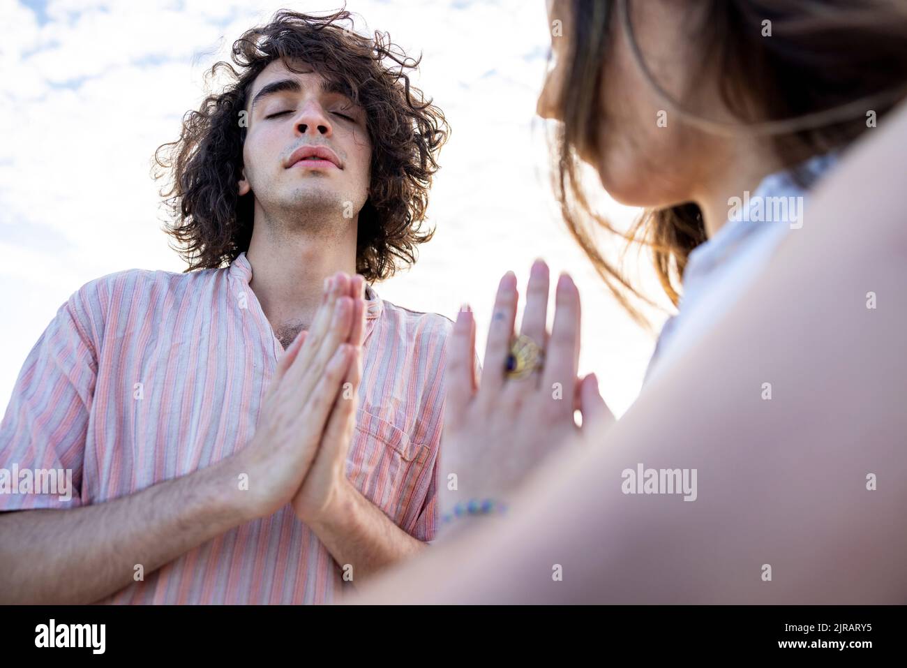 Junges Paar meditiert mit zusammengekrallten Händen Stockfoto