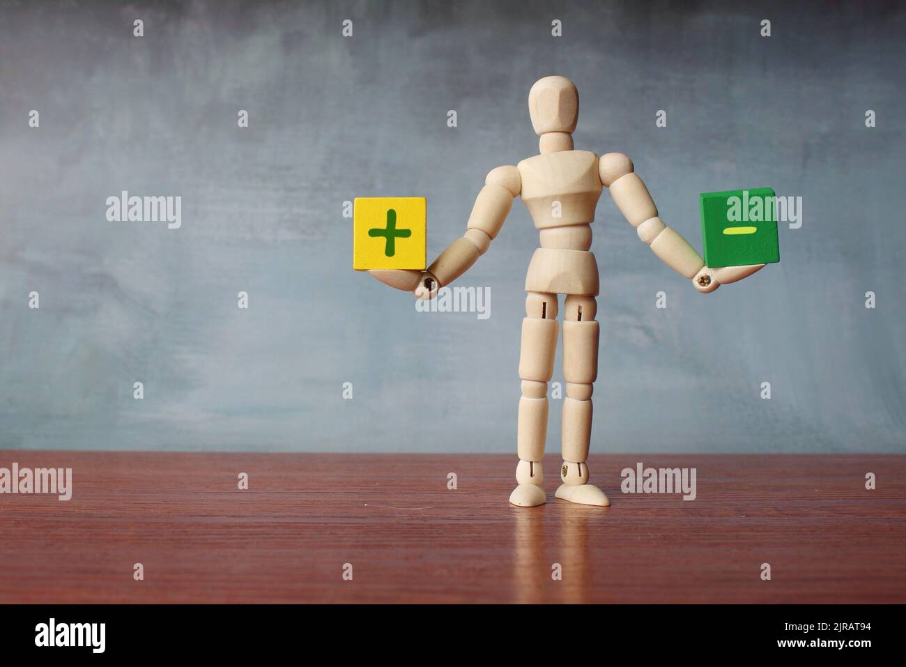 Vor- und Nachteile Gleichgewicht Konzept. Hölzerne menschliche Figur balanciert Holzwürfel mit Plus- und Minuszeichen. Platz für Text kopieren Stockfoto