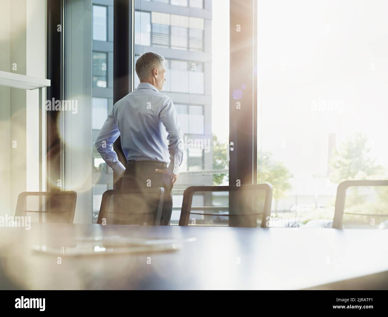 Ein Geschäftsmann blickt durch das Fenster in den Konferenzraum Stockfoto