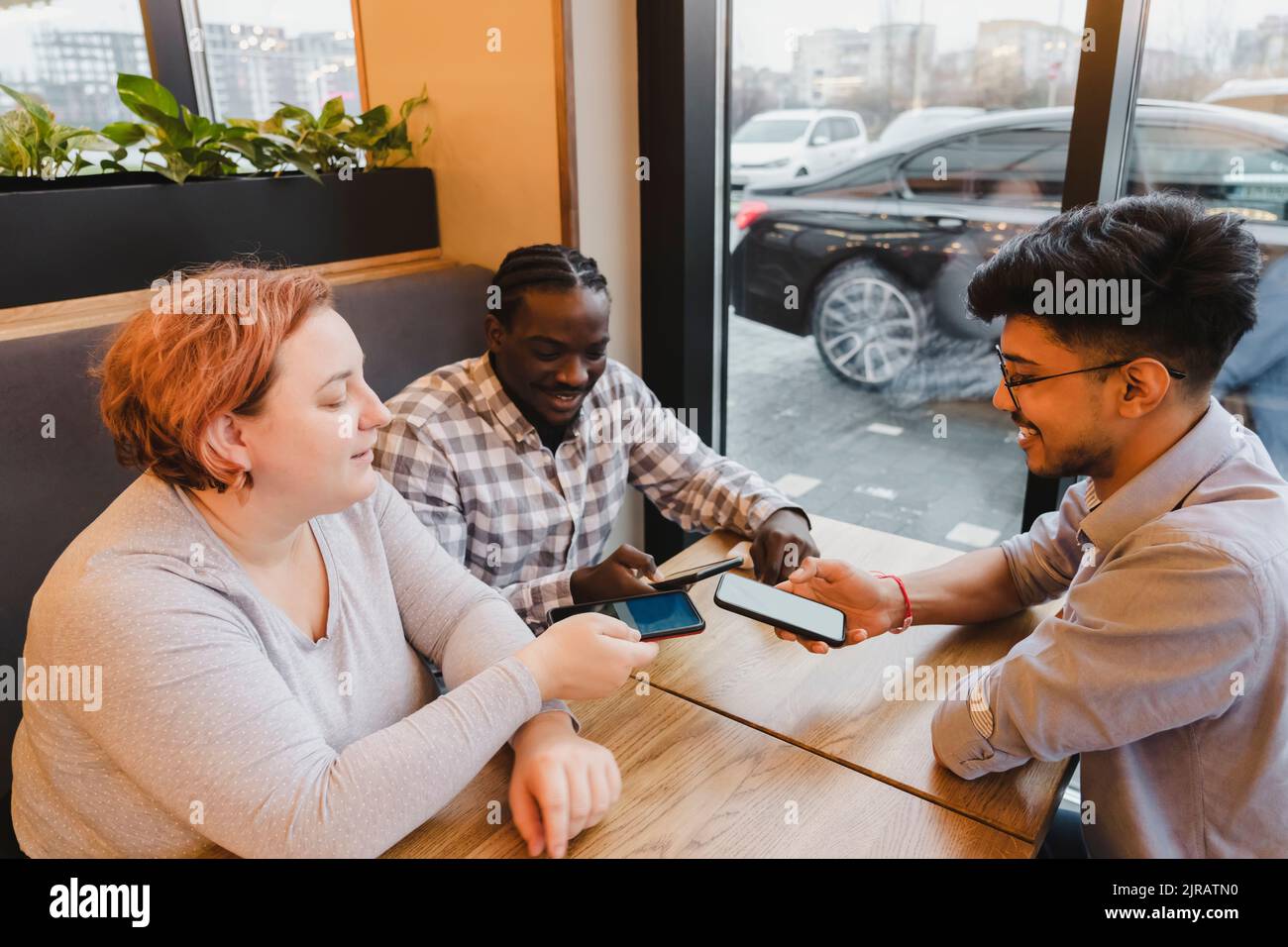Glückliche Freunde teilen Daten über Smartphones im Café Stockfoto