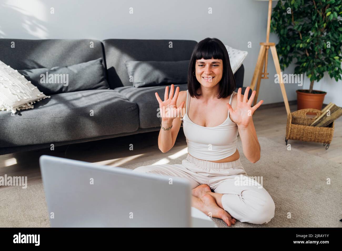 Frau winkt beim Videoanruf mit den Händen auf den Laptop Stockfoto