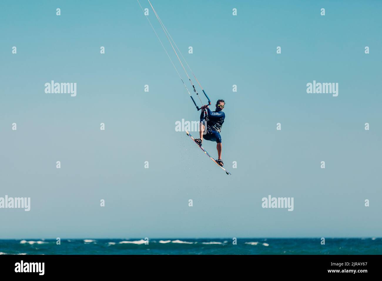 Reifer Mann Kiteboarding in der Luft über Meer an sonnigen Tag Stockfoto