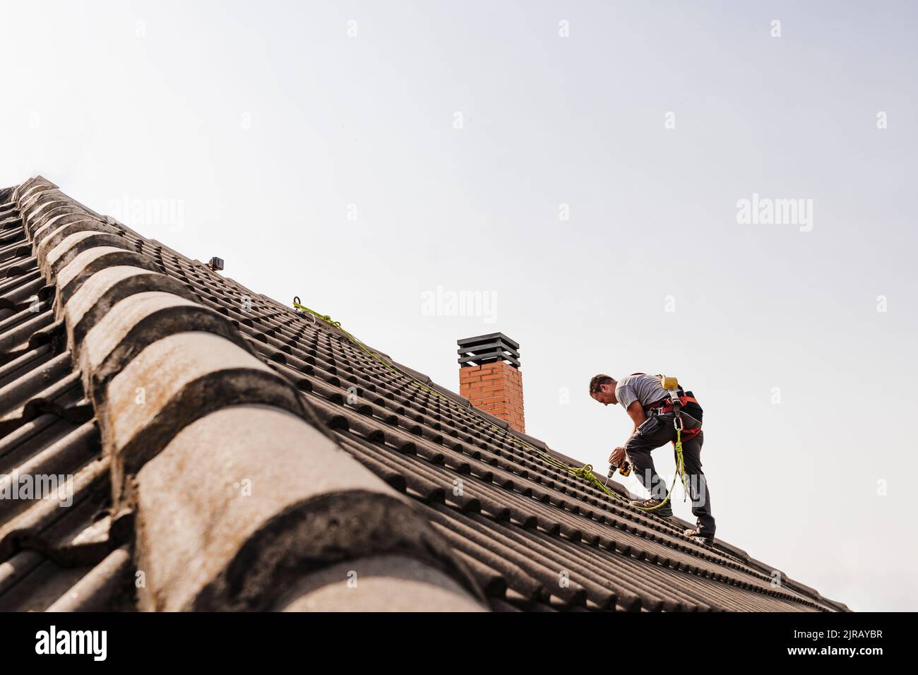 Techniker, der Elektrowerkzeug auf dem Dach verwendet Stockfoto