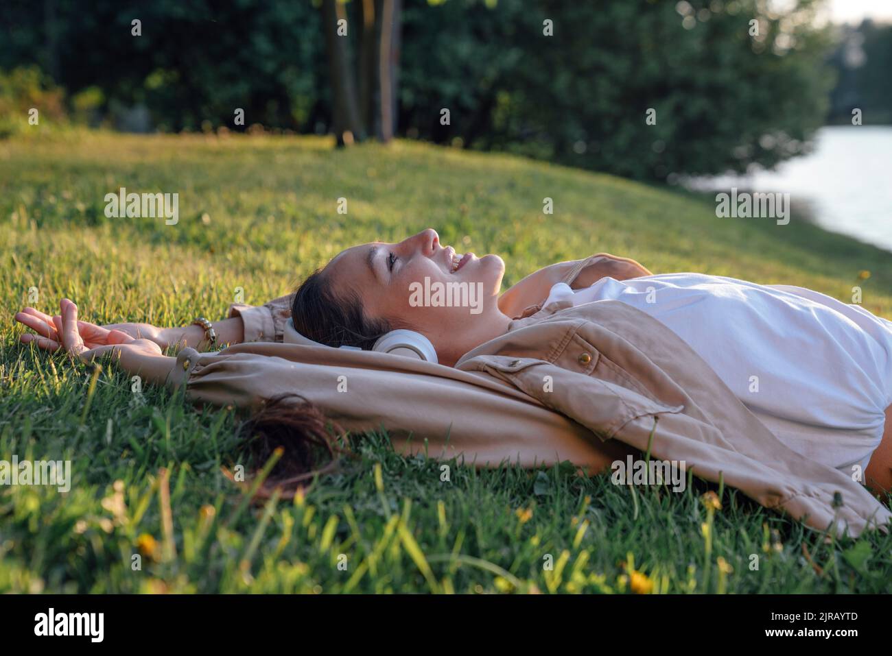 Lächelnde Frau, die sich im Park auf Gras legt Stockfoto