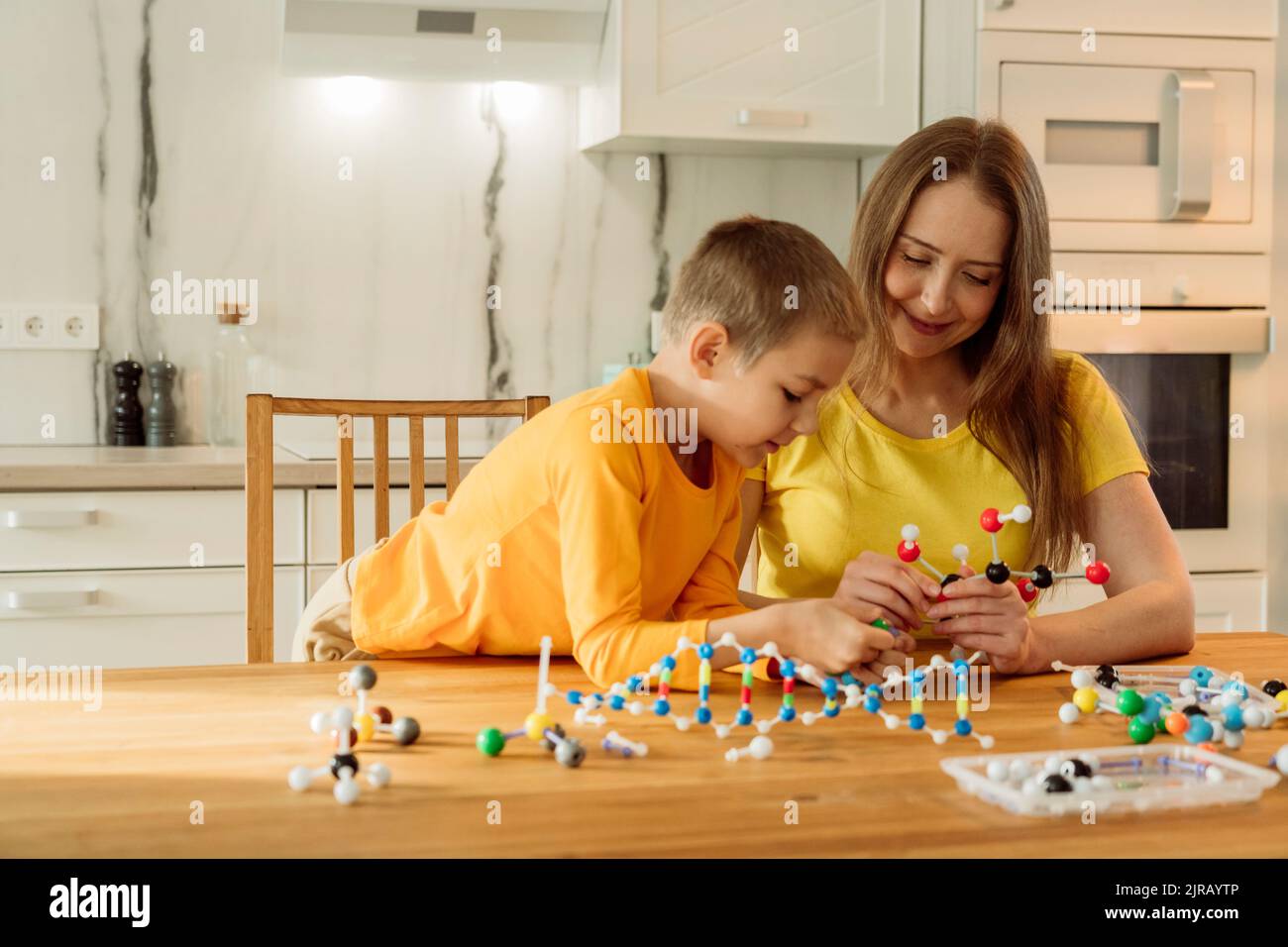 Mutter und Sohn bauen zu Hause molekulare Strukturen auf dem Tisch Stockfoto