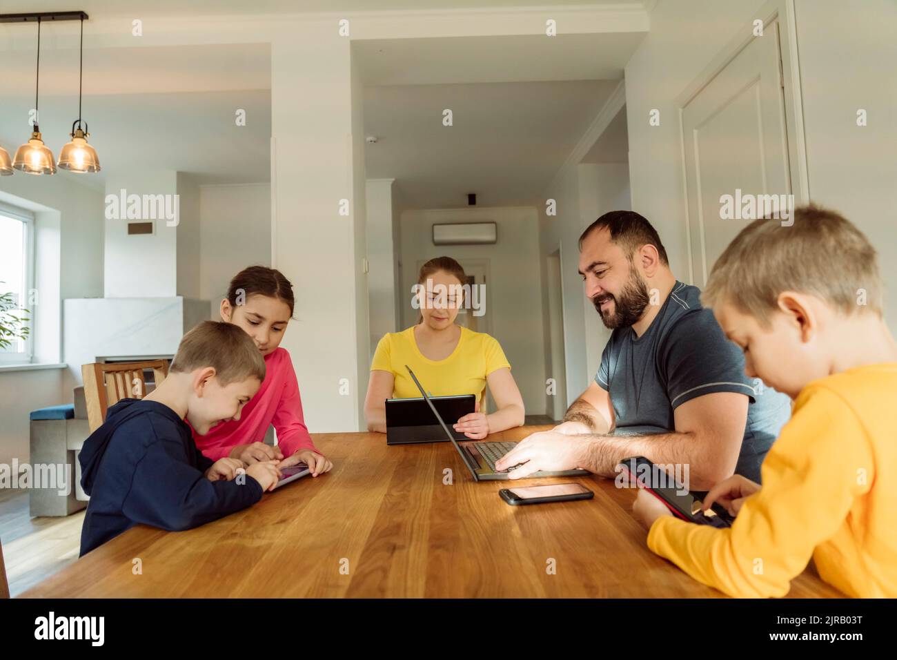 Eltern mit Kindern, die zu Hause drahtlose Technologien nutzen Stockfoto
