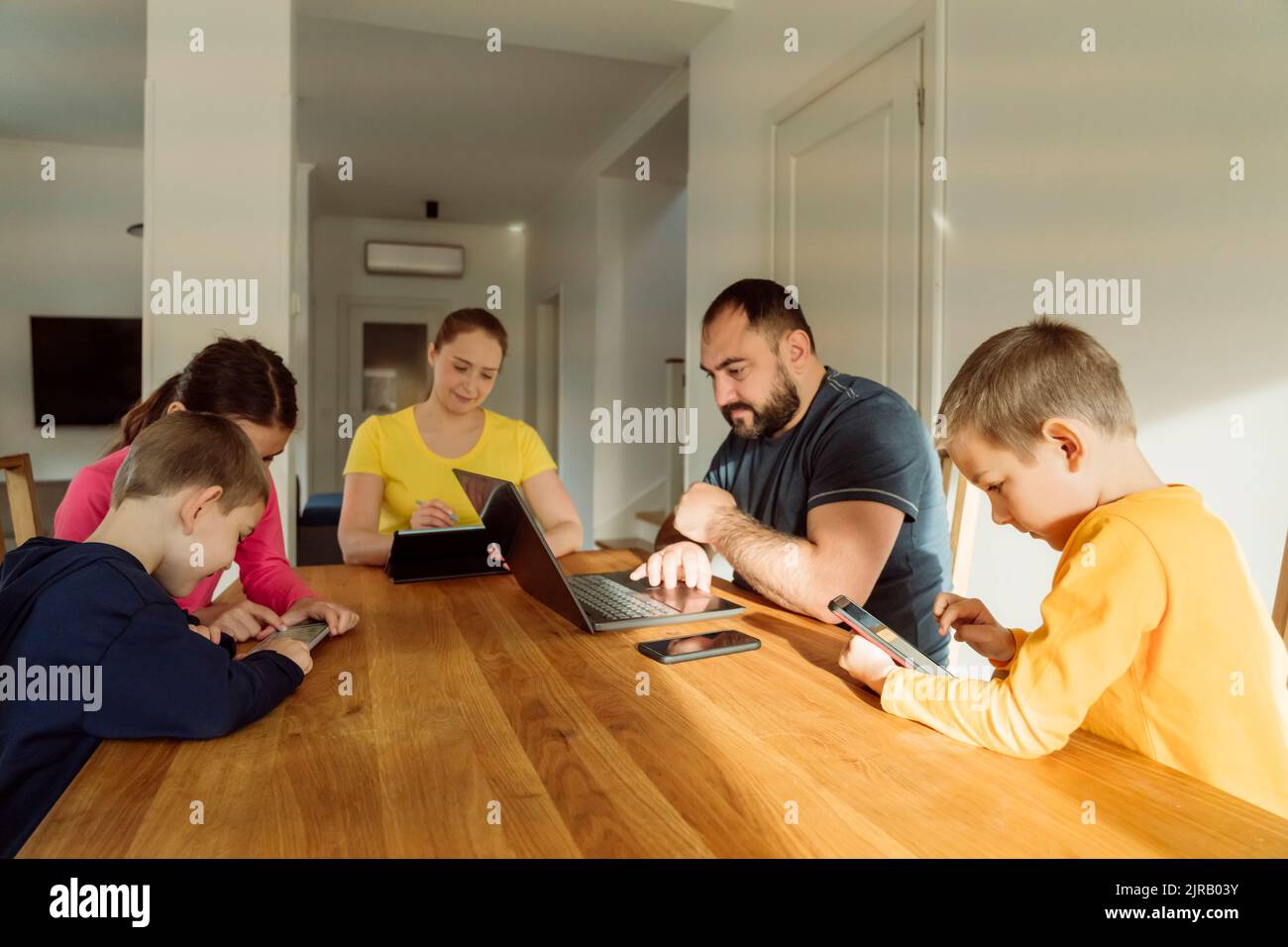 Familie, die drahtlose Technologien auf dem Tisch zu Hause verwendet Stockfoto