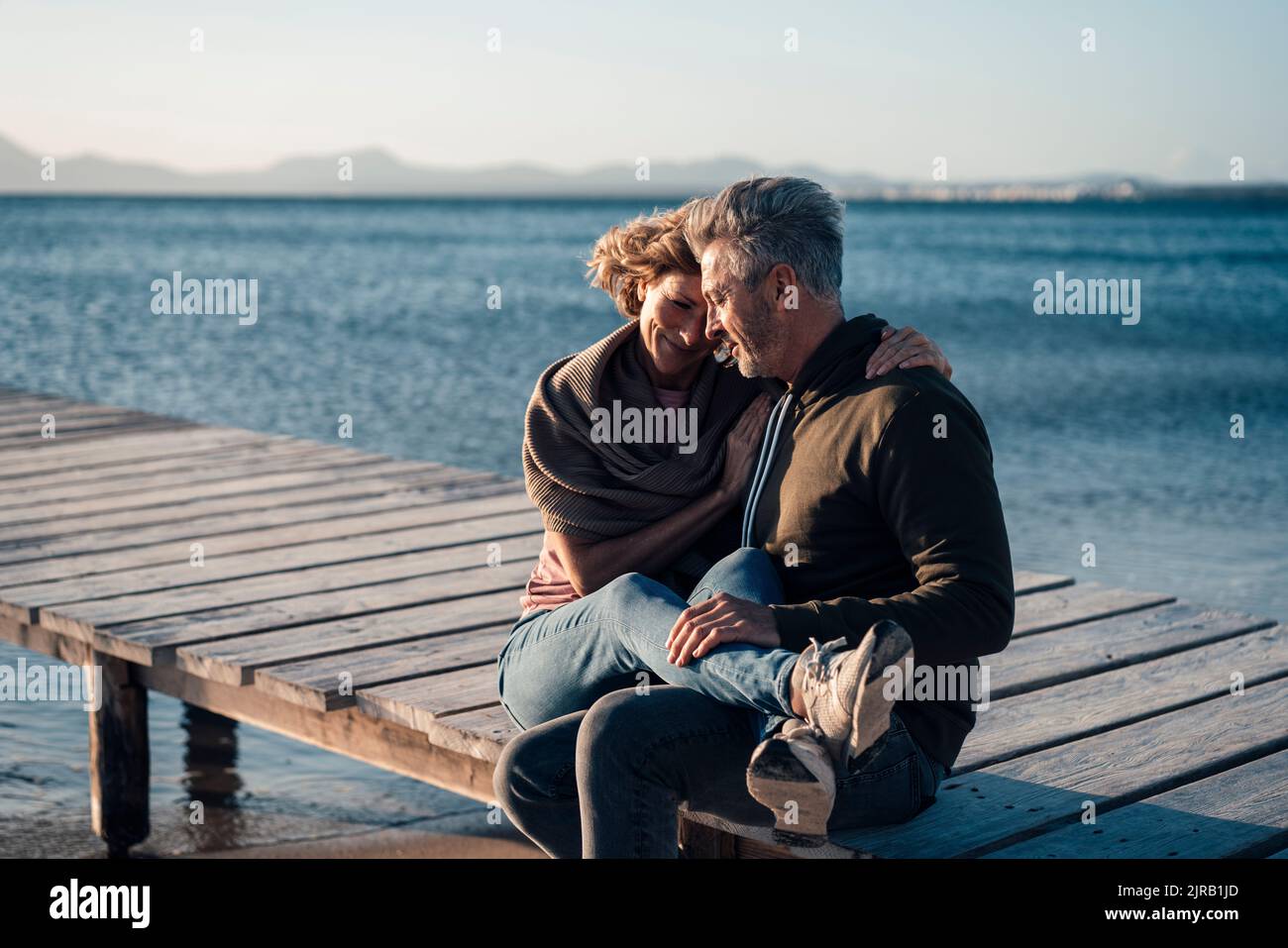 Glückliches reifes Paar, das auf dem Steg sitzt Stockfoto