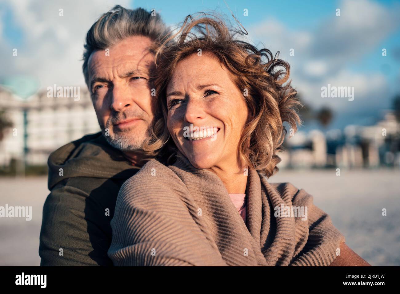 Lächelnde blonde Frau mit Mann, der Urlaub am Strand genießt Stockfoto