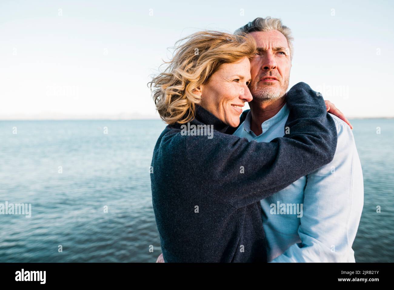 Lächelnder reifer Mann mit Frau, die Urlaub am Strand genießt Stockfoto