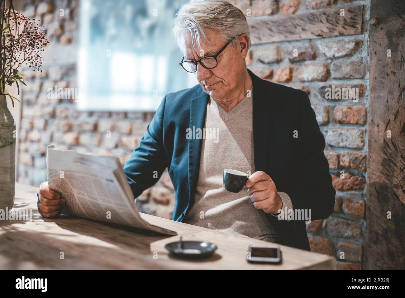 Geschäftsmann liest Zeitung und hat Kaffee im Café Stockfoto