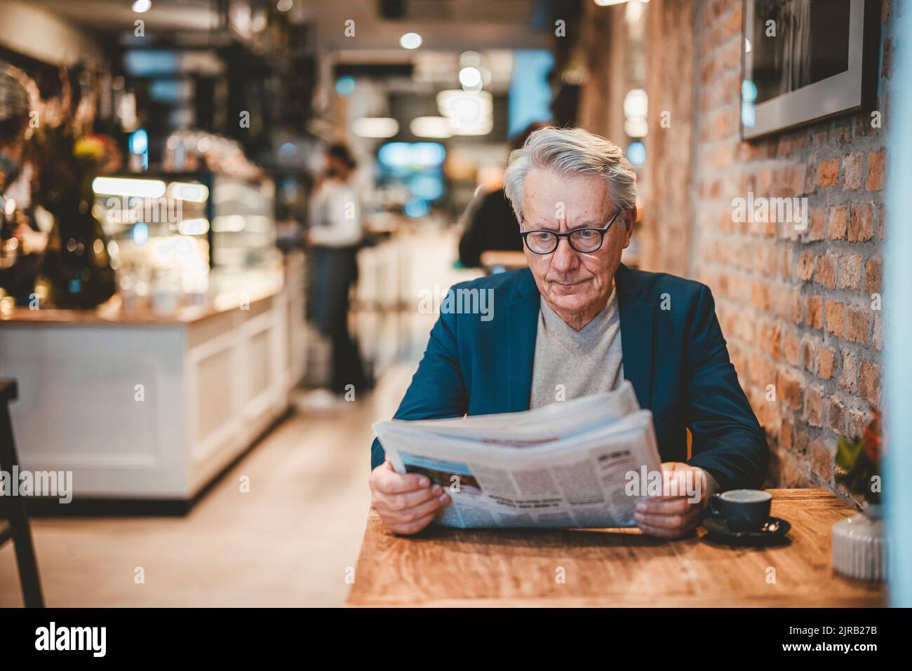Ein älterer Geschäftsmann liest die Zeitung im Café Stockfoto
