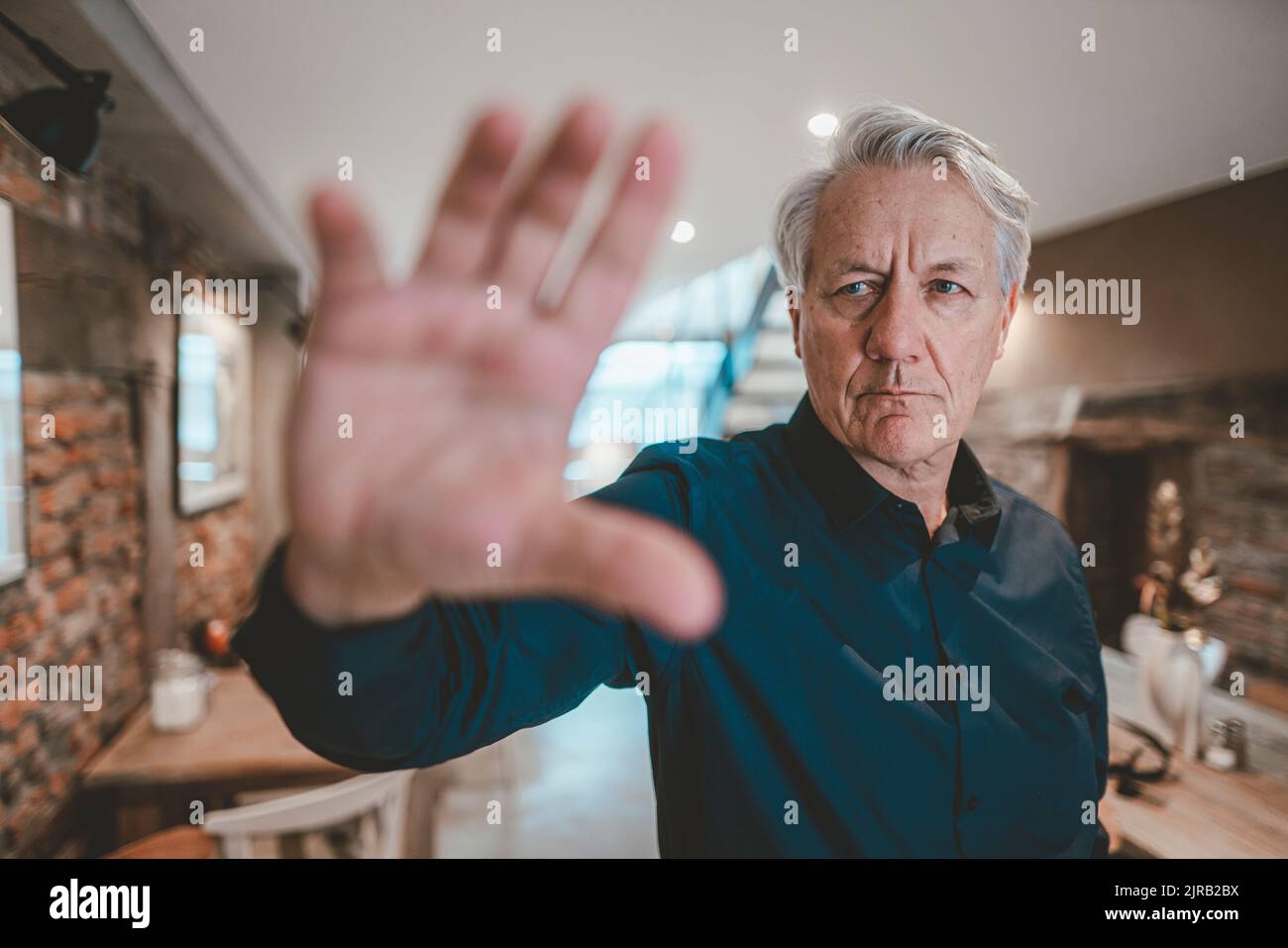 Älterer Mann macht im Café eine Stoppgeste Stockfoto