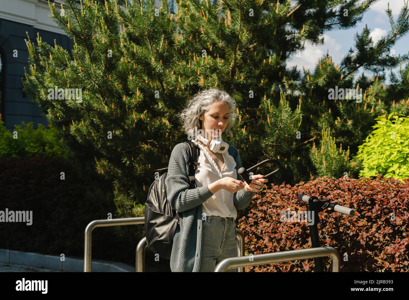 Frau hält Sperre durch elektrischen Roller schieben Stockfoto