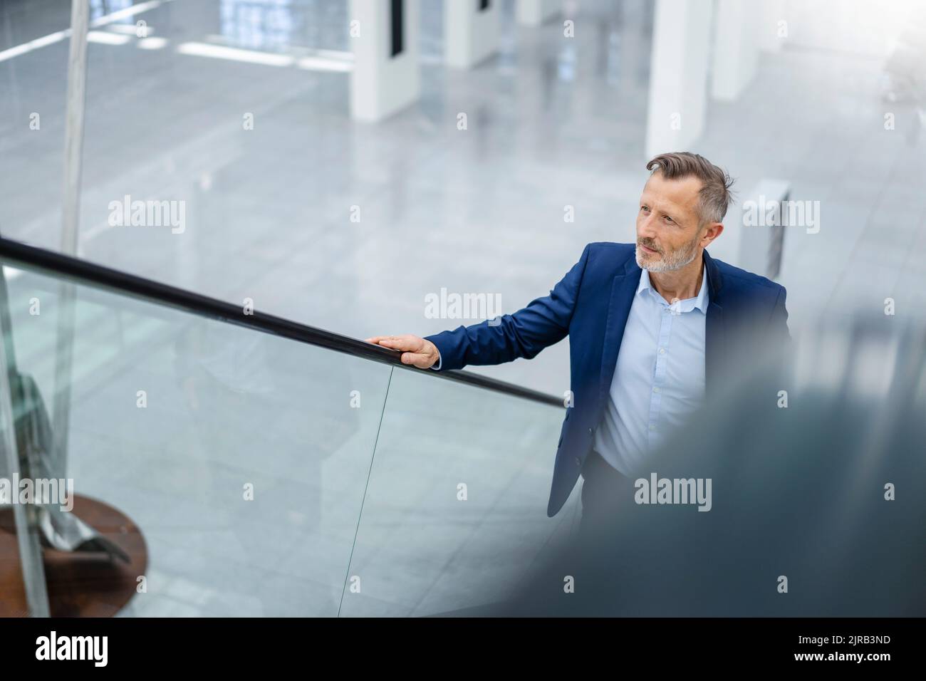 Reifer Geschäftsmann, der auf die Rolltreppe hochzieht Stockfoto