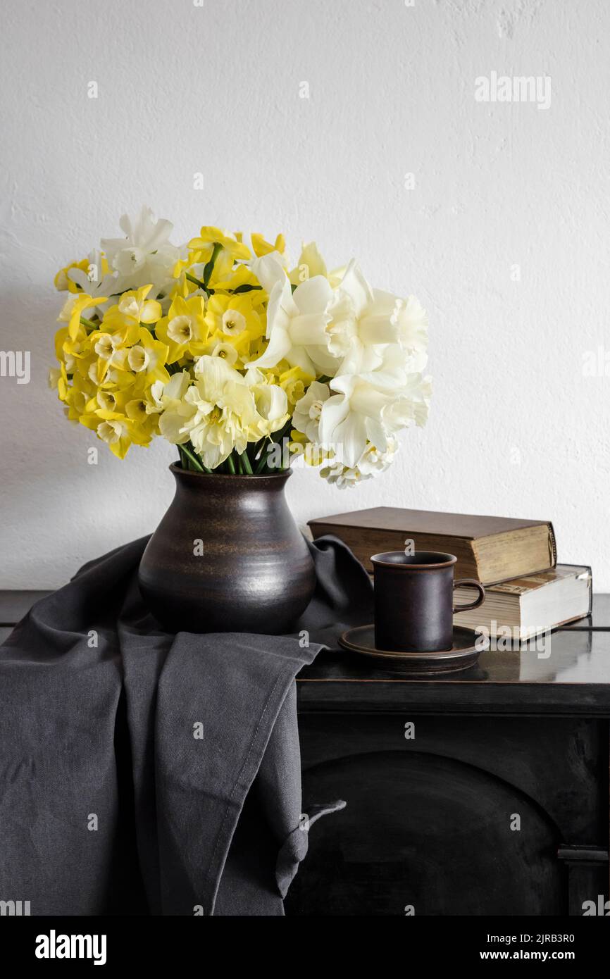 Studioaufnahme einer Vase mit blühenden Narzissen, die auf einem rustikalen Tisch stehen Stockfoto