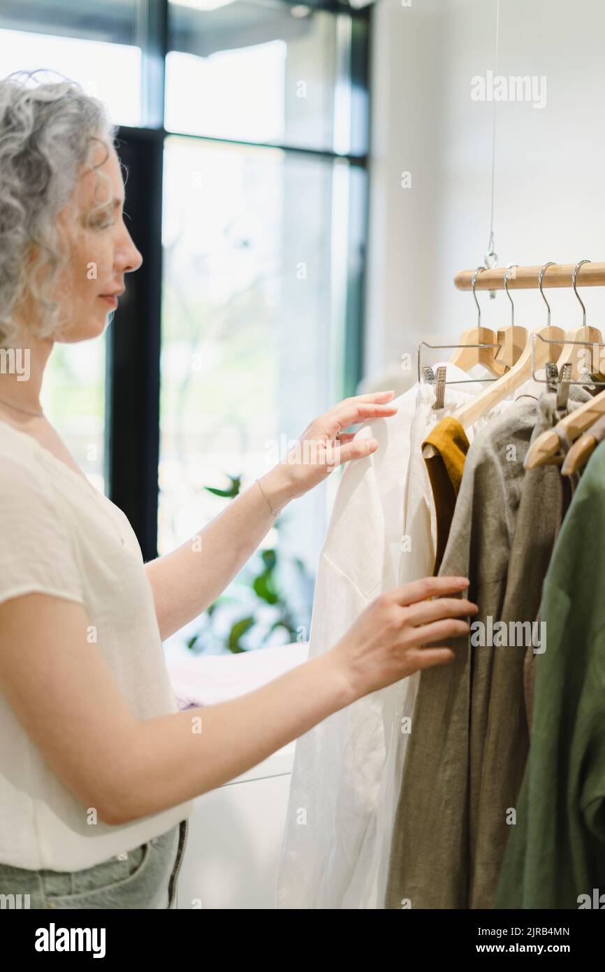 Frau wählt Hemd im Geschäft Stockfoto