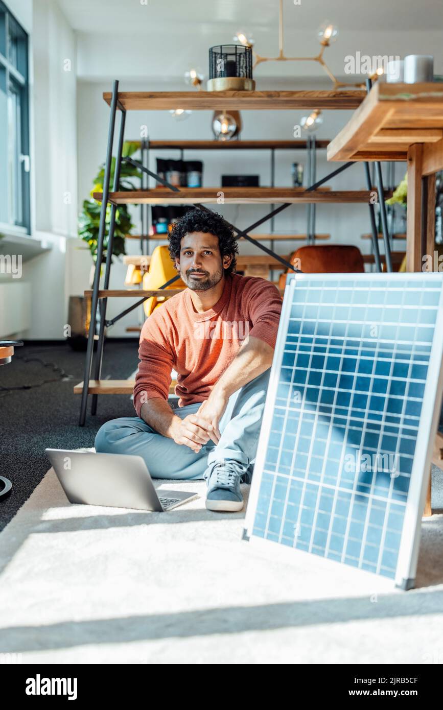 Geschäftsmann mit Laptop und Solarpanel am Arbeitsplatz Stockfoto