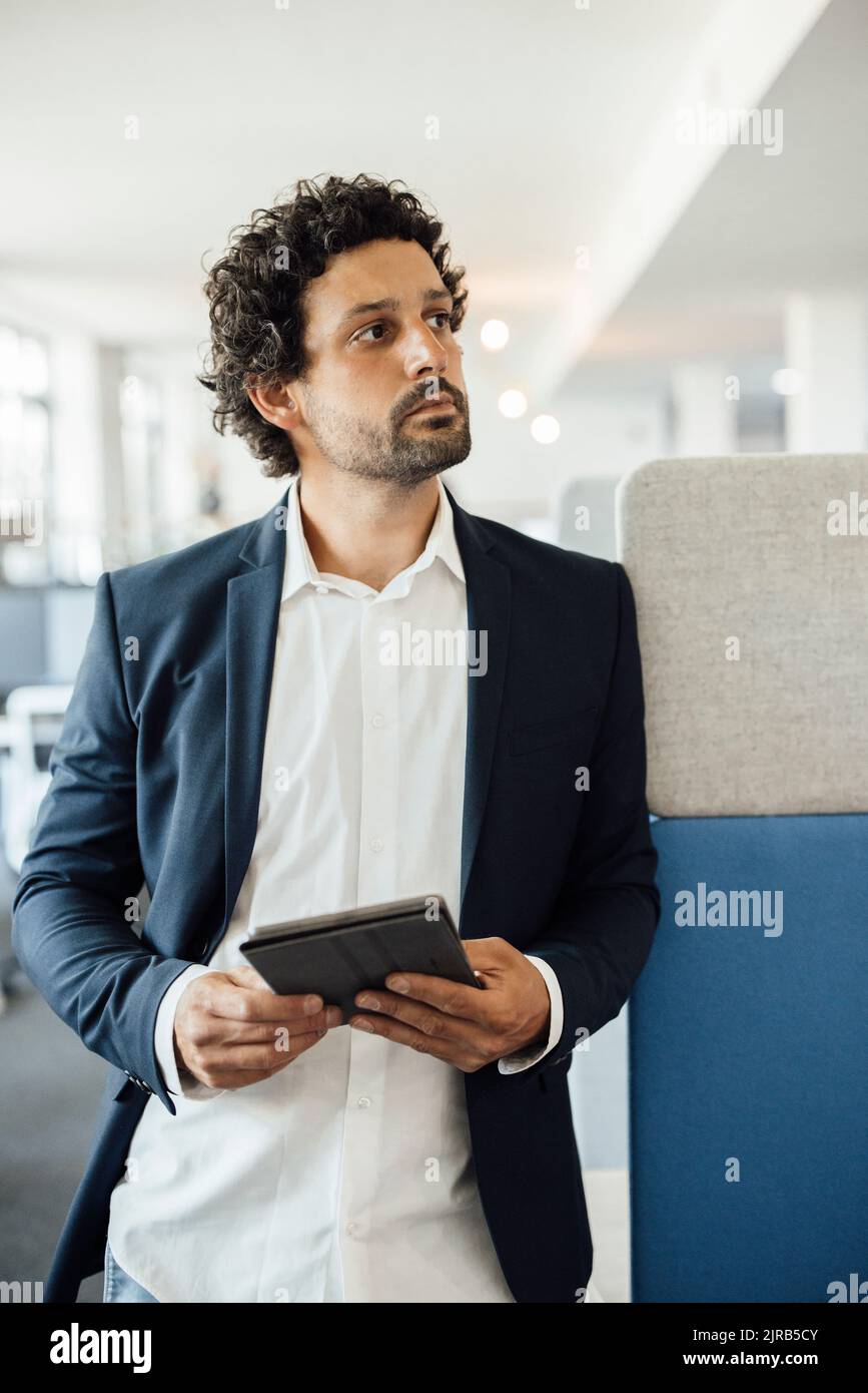 Besinnlicher Geschäftsmann mit Tablet-PC am Arbeitsplatz Stockfoto