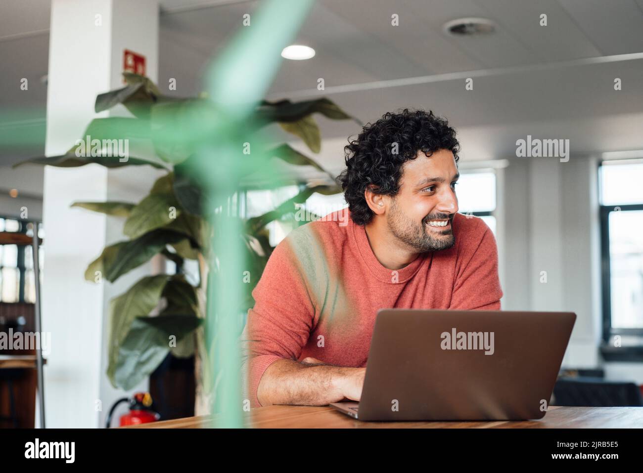Lächelnder Geschäftsmann mit Laptop am Arbeitsplatz Stockfoto