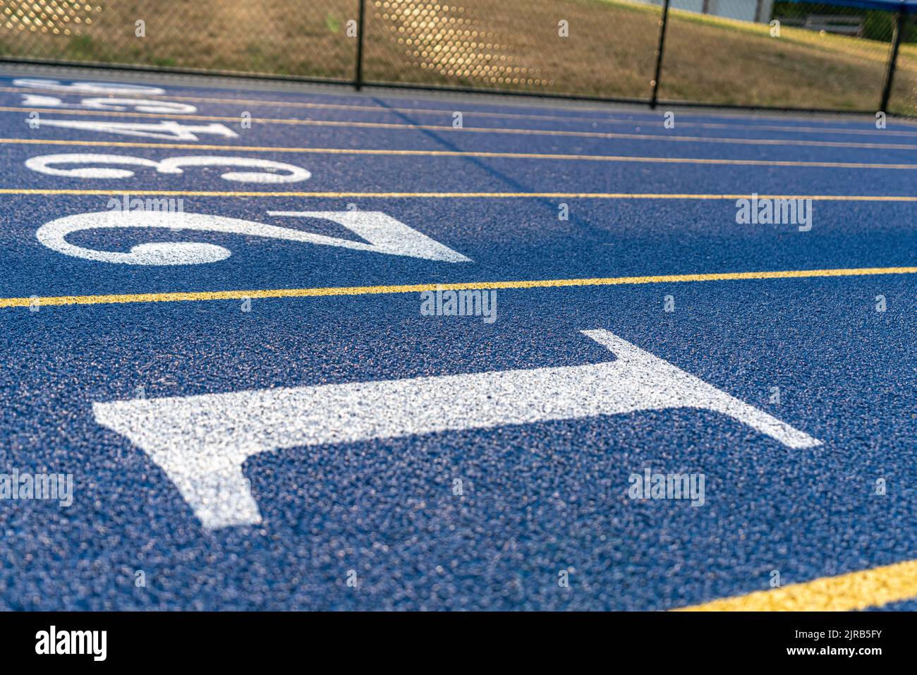 Inspirierende Nahaufnahme einer neuen blauen Laufstrecke mit gelben Spurlinien und anderen Markierungen. Stockfoto