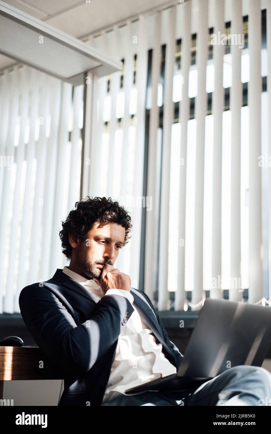 Konzentrierter Geschäftsmann mit Laptop am Arbeitsplatz Stockfoto