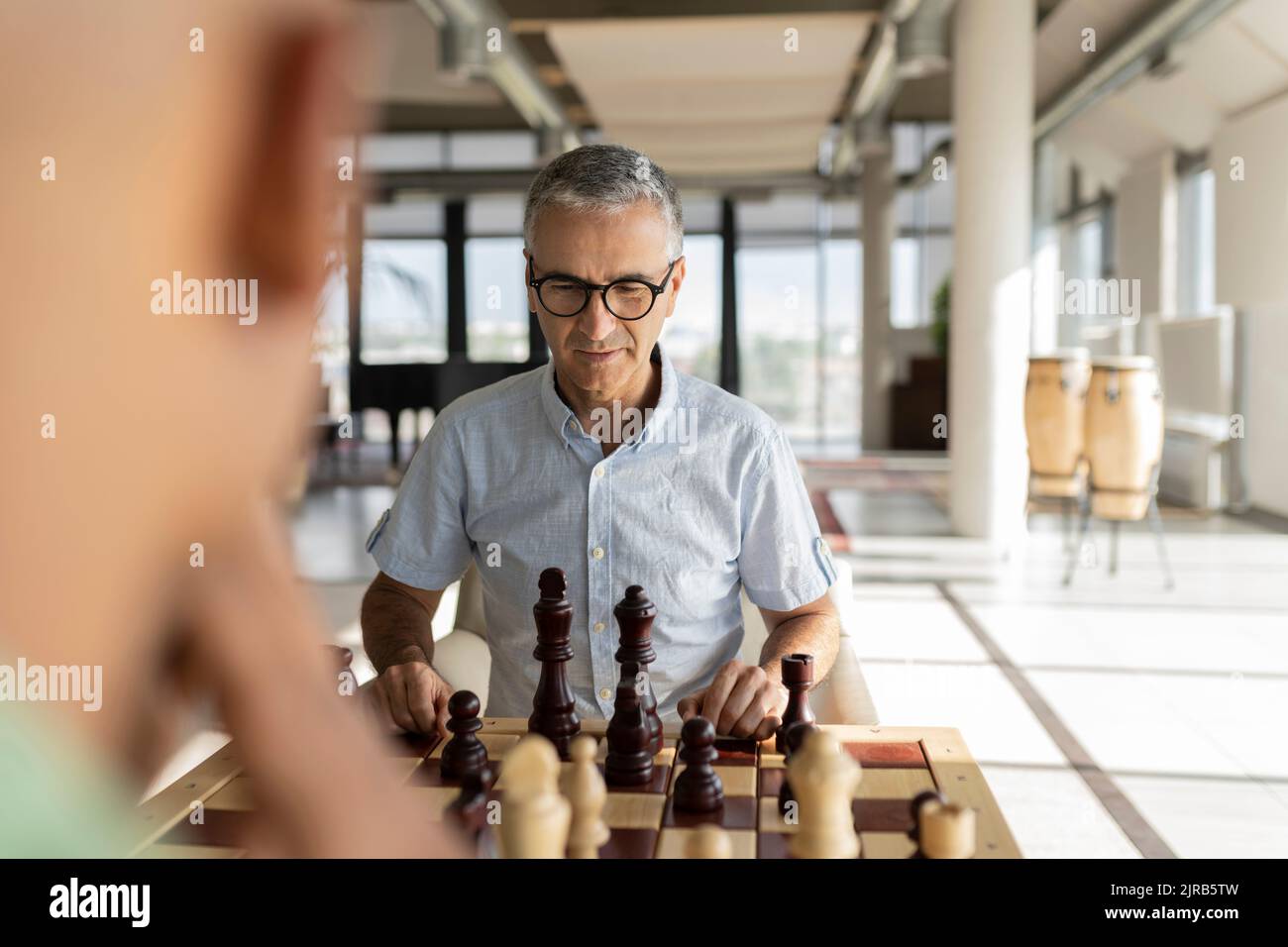 Reifer Geschäftsmann, der mit einem Kollegen im Büro Schach spielt Stockfoto