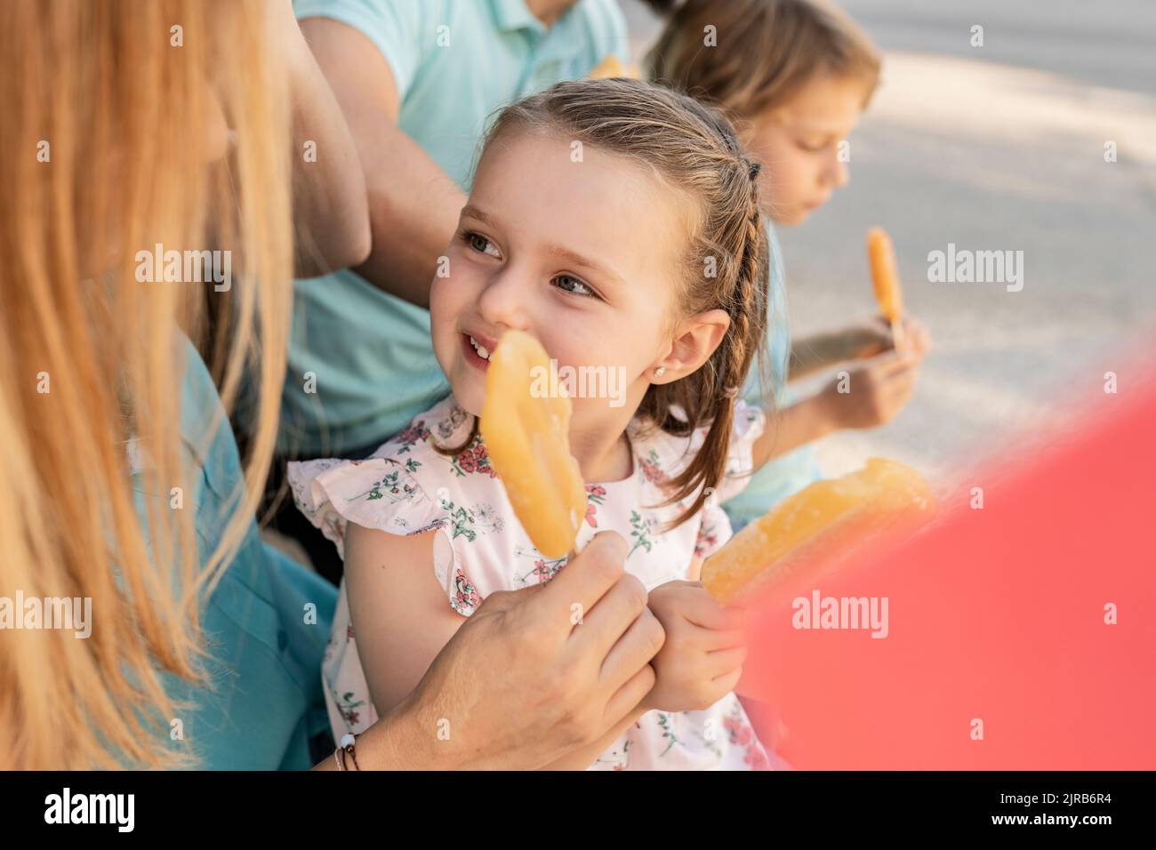 Nettes Mädchen mit Eis Pop Blick auf Mutter sitzen von Vater und Bruder Stockfoto
